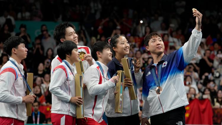 North Korean South Korean athletes take selfies as they share an Olympic podium